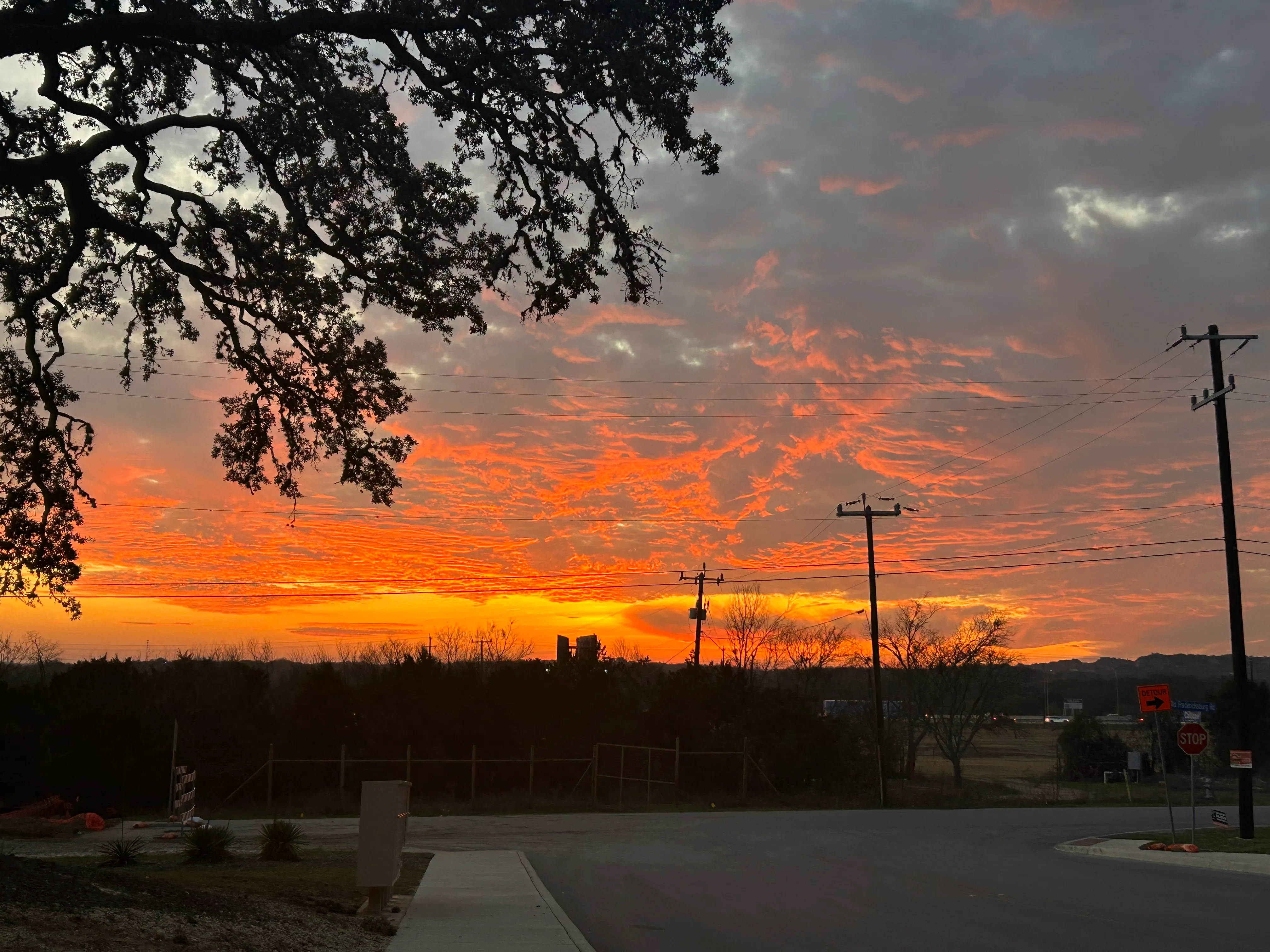 Dramatic sunset sky with power lines silhouetted against orange and red clouds